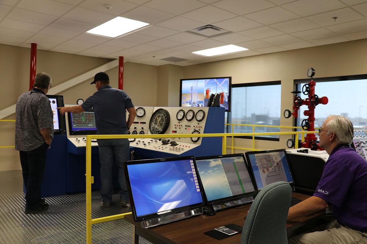 Three people in well control room.